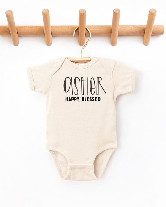 Beige baby onesie with 'asher Happy, Blessed' text on a white background